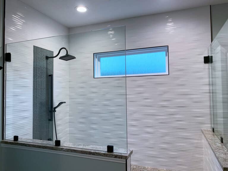 Bathroom remodeling contractor project featuring a sleek, modern shower with textured walls, rainfall showerhead, and a horizontal window.