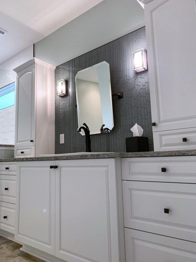 Bathroom remodeling contractor project featuring a modern vanity with white cabinetry, granite countertop, and sleek black fixtures.